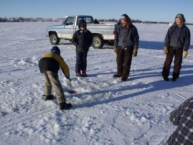 Mario cleans out a freshly dug ice fishing hole.